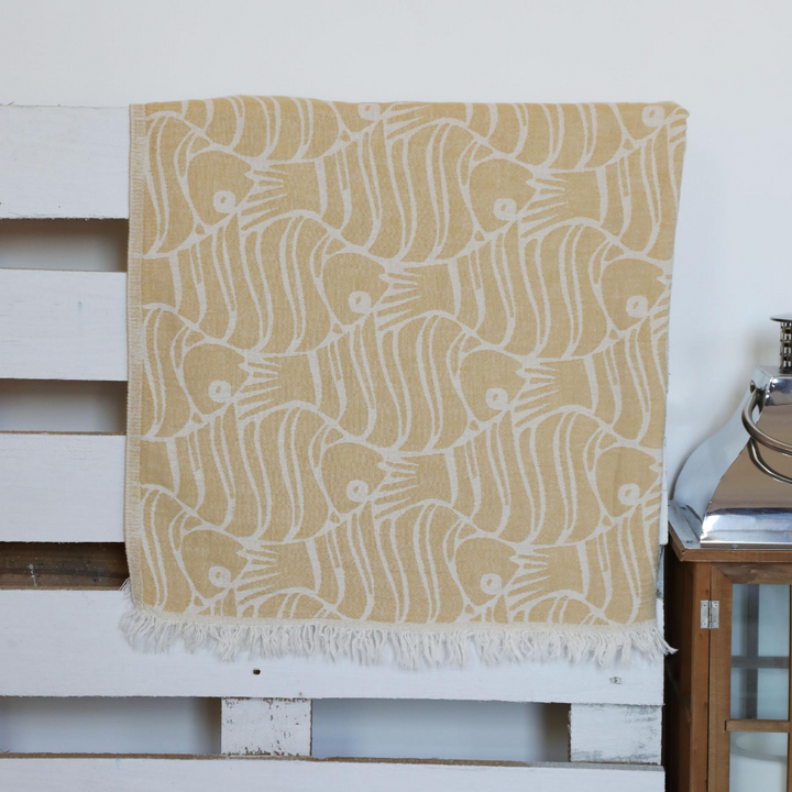 Mustard color, soft Turkish beach towel has fish designs